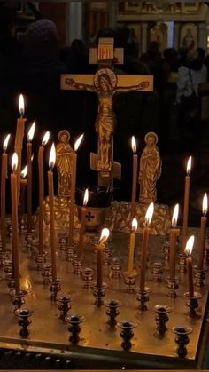 many candles are lit in front of a crucifix