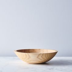 a wooden bowl sitting on top of a white marble counter next to a gray wall