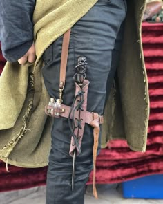 a person wearing leather garb and holding a bag with chains on it's belt