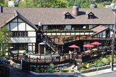 an aerial view of a restaurant with tables and umbrellas on the patio, surrounded by trees