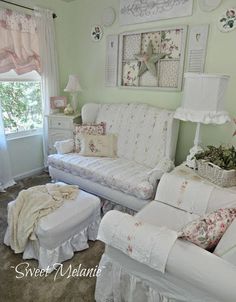 a living room filled with white furniture and flowers on the wall above it's windows