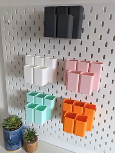 there is a wall with several different colored vases on it and a potted plant next to it