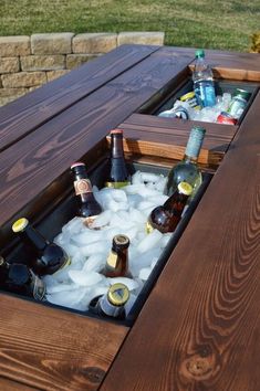 an outdoor table with ice and beer bottles in it