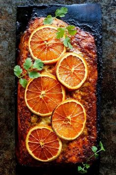 sliced oranges and herbs on top of a sheet of baking paper with some garnish