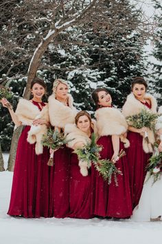 a group of women in red dresses and fur stoles standing next to each other