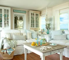 a living room filled with white furniture and lots of wood flooring next to windows