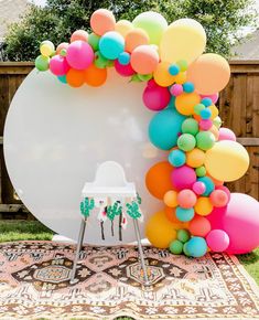 an arch made out of balloons on top of a rug in front of a fence