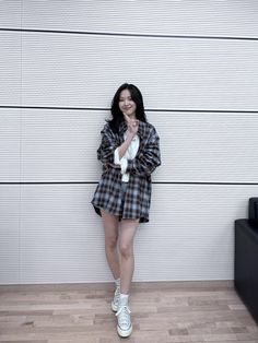 a woman standing in front of a white wall holding a stuffed animal and smiling at the camera