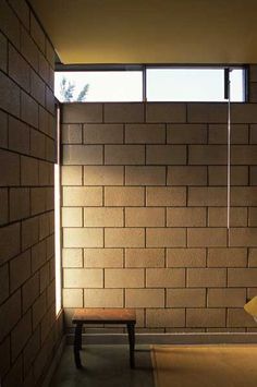 a bench sitting in the middle of a room next to a brick wall and window