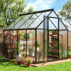 a small greenhouse in the middle of a yard with potted plants and flowers inside