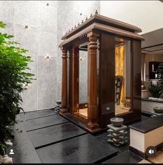 a small wooden structure sitting in the middle of a room next to a potted plant