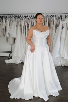 a woman is standing in front of some wedding dresses