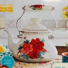 a white tea kettle with red flowers painted on it