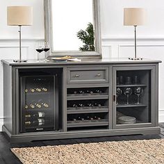 a wine cabinet with several bottles and glasses on it in front of a large mirror