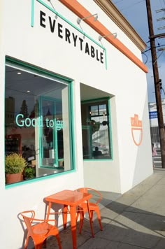 an orange table and chairs outside of a storefront with the words,'everytable'written on it