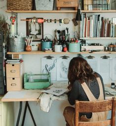 a woman sitting at a desk in front of a bookshelf filled with lots of books