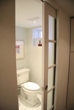 a white toilet sitting inside of a bathroom next to a doorway leading into another room