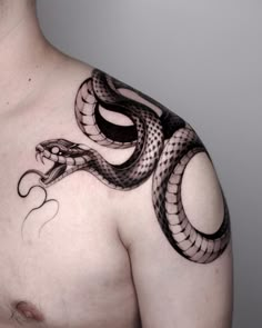 a man's chest with a snake tattoo on his arm and shoulder, in black ink