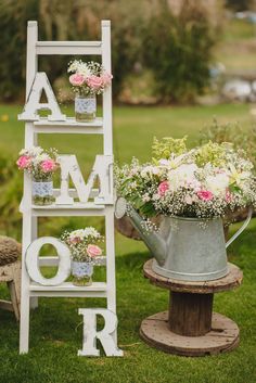 an old ladder is used as a planter for flowers and vases in the shape of letters