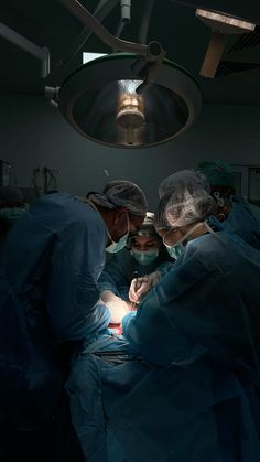 three doctors performing surgery on a patient in an operating room at the hospital with lights on