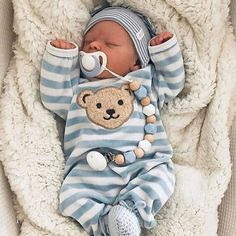 the baby is wearing a blue and white striped outfit with a teddy bear on it