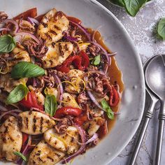 a white bowl filled with meat and vegetables on top of a table next to silverware