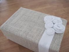 an image of a gift wrapped in burlap and white ribbon on the floor