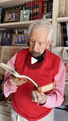 an old man reading a book in front of bookshelves