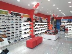 the inside of a shoe store filled with lots of shoes on display and red walls