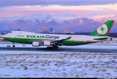 an eva air cargo plane taking off from the tarmac at dusk with mountains in the background