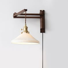 an old fashioned light fixture hangs on the wall next to a white wall and brown pipe