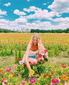 a woman kneeling down in a field with flowers