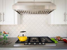 a stove top oven sitting inside of a kitchen next to white cabinets and counter tops