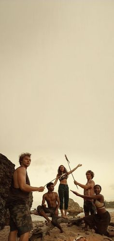 a group of men standing on top of a beach next to each other holding sticks