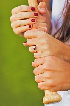 someone is holding their hand on the handle of a baseball bat and wearing red nail polish