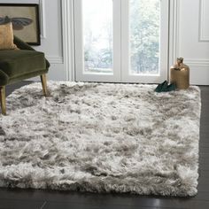 a living room area with a chair and rug on the floor in front of a window