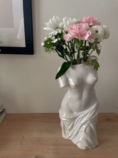 a vase with flowers in it sitting on a table next to a framed photo and books