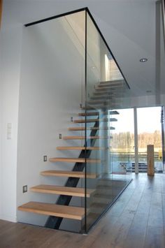 there is a glass stair case in the house with wood steps and railings on both sides