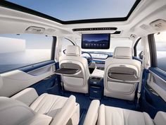 the interior of a vehicle with all white leather seats and blue trims, looking out over the ocean