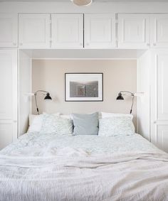 a bed with white linens and pillows in a bedroom