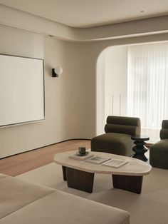 a living room with two couches and a table in front of a projector screen