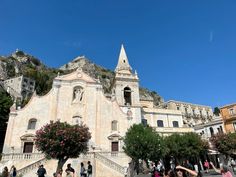 people are walking around in front of an old church