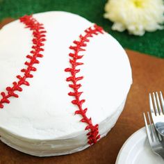 a baseball cake with red stitches on it and a fork sitting next to the cake