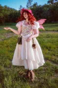 a woman in a white dress and pink hat is standing on the grass with her arms out