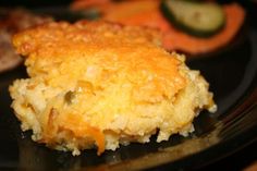 a close up of a piece of food on a plate with vegetables in the background