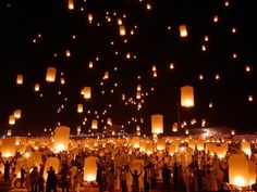 many people are flying lanterns in the night sky with lights on them, and there is no image here to provide a caption for