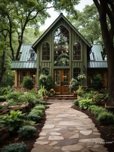 a house that is surrounded by trees and plants in the front yard, with a stone path leading up to it