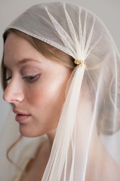 a woman wearing a white veil with a flower on it's head and her eyes closed