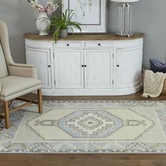 a blue rug in a living room with two chairs and a vase filled with flowers