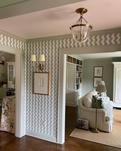 a living room filled with furniture and a chandelier hanging from the ceiling in front of a doorway